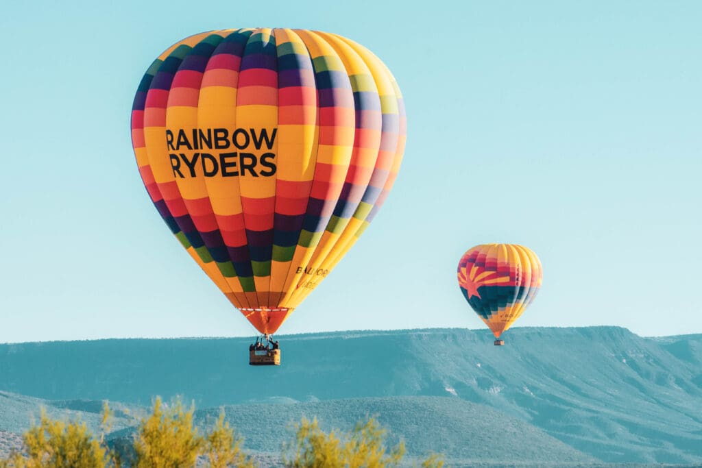 Two Rainbow Ryders hot air balloons floating over the Sonoran Desert.