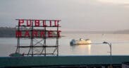 The Pike Place Market sign overlooking a boat cruising Seattle's Puget Sound.
