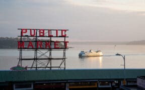 The Pike Place Market sign overlooking a boat cruising Seattle's Puget Sound.