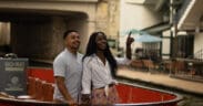 A black couple embraces, looking over the San Antonio River Walk.