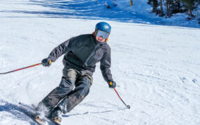 A skier is going downhill on a Snowbowl mountain trail.