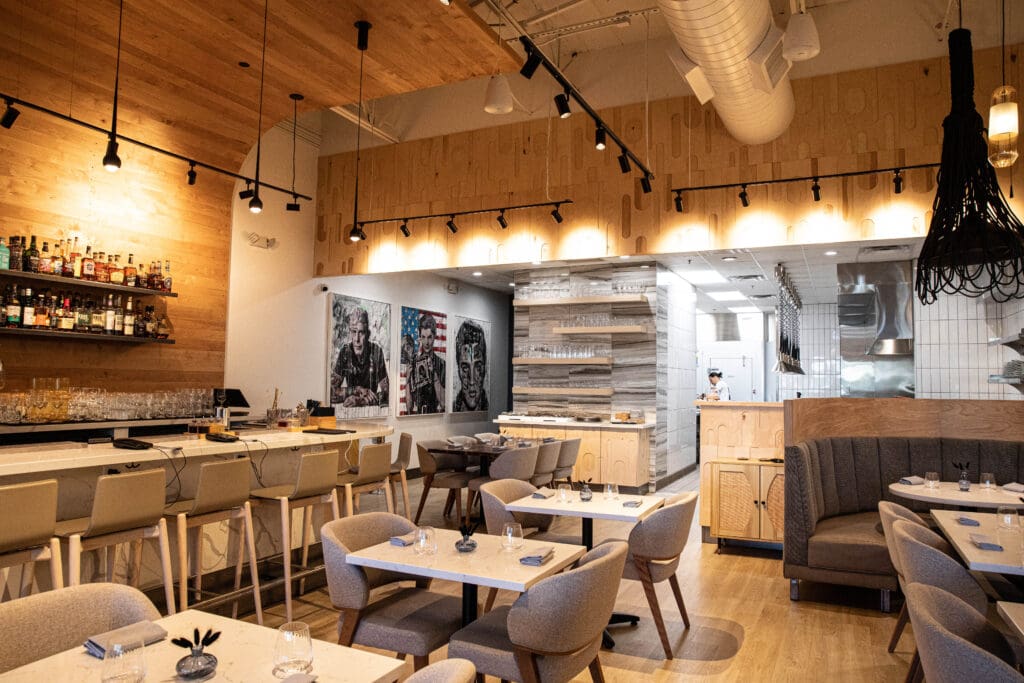 Fine dining tables set for service with wood beam ceilings at COURSE.