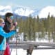 A man and woman with ski poles in Grand County Colorado on a mountain with trees and snow.