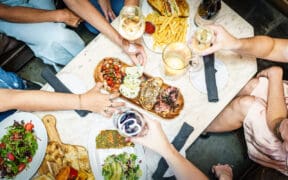 People visiting The Living Room restaurant share a bruschetta board, salad and drinks at a table.