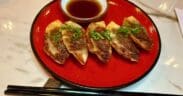 Tiki Taka's Gyoza on a plate next to chopsticks with a small bowl ofsherry dip.