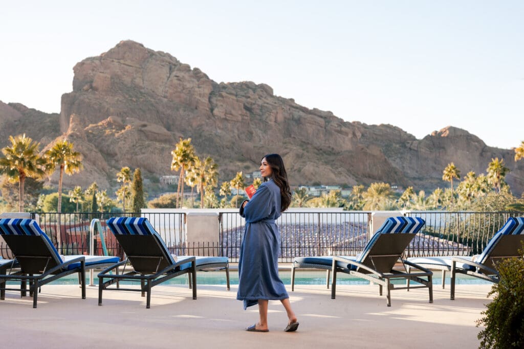 A woman stands in a robe outside at the Omni Montelucia with mountain views in the background.