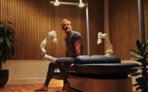 A man sits on a massage table at the AWAY Spa at W Scottsdale next to the Aescape AI massage tool.