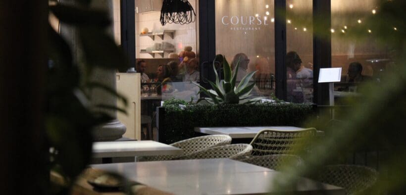 COURSE Restaurant Patio with outdoor seating and an expansive window showing the interior of the restaurant,