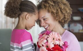 A daughter and mother touch foreheads after the daughter presented her mom with flowers for Mother's Day.