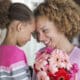 A daughter and mother touch foreheads after the daughter presented her mom with flowers for Mother's Day.