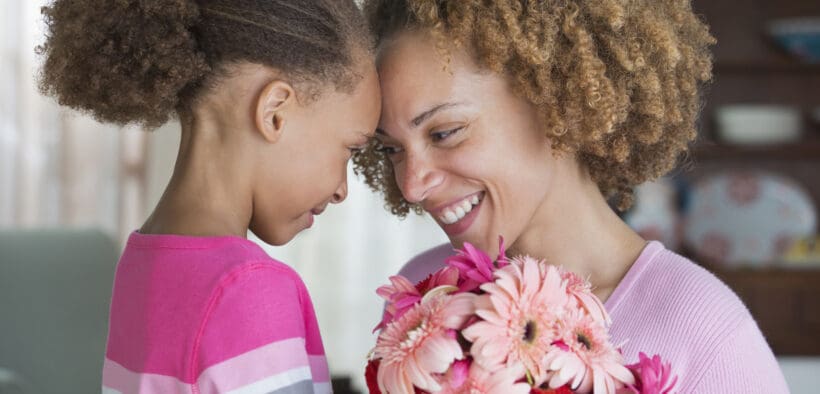 A daughter and mother touch foreheads after the daughter presented her mom with flowers for Mother's Day.