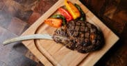 A Tomahawk steak and peppers on a cutting board at J&G Steakhouse at The Phoenician