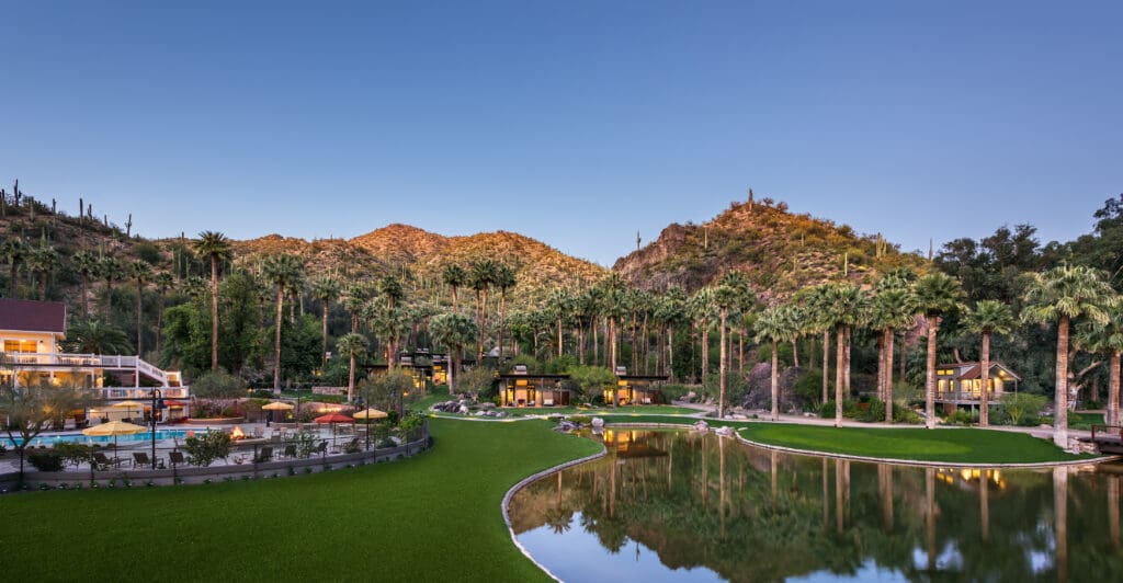 Castle Hot Springs resort with a mountain backdrop, bond, pool and palm trees.
