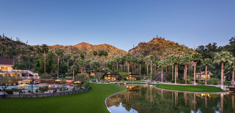 Castle Hot Springs resort with a mountain backdrop, bond, pool and palm trees.