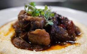 A plate of Oxtail on grits made by Dana Dumas for SugarJam The Southern Kitchen's Juneteenth menu.