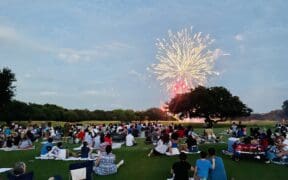 Guests of the Hyatt Regency Hill Country Resort and Spa sit on the property's lawn watching fireworks.