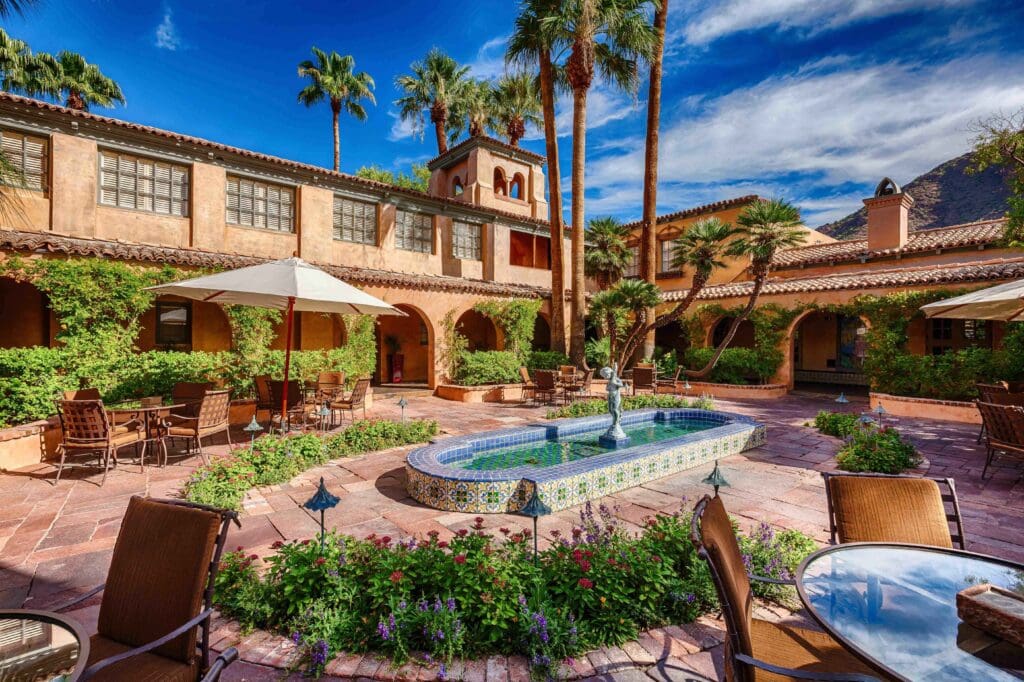 Royal Palms Resort and Spa courtyard with vine coverd plants, a fountain and seating areas.
