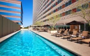 The rooftop pool at Sheraton Phoenix Downtown next to the high-rise hotel with lounge chairs and umbrellas.