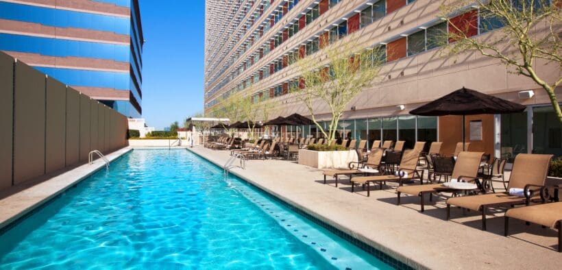 The rooftop pool at Sheraton Phoenix Downtown next to the high-rise hotel with lounge chairs and umbrellas.
