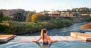 A woman in a bathing suit and ponytail is in geothermal plunge pool at The Springs Resort and Spa, looking over the San Juan River.