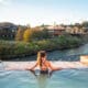 A woman in a bathing suit and ponytail is in geothermal plunge pool at The Springs Resort and Spa, looking over the San Juan River.
