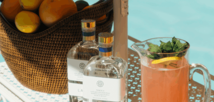 A basket of oranges sits next to two bottles of LALO and a pitcher of grapefruit juice for Club Soleil pop up at the The Global Ambassador.