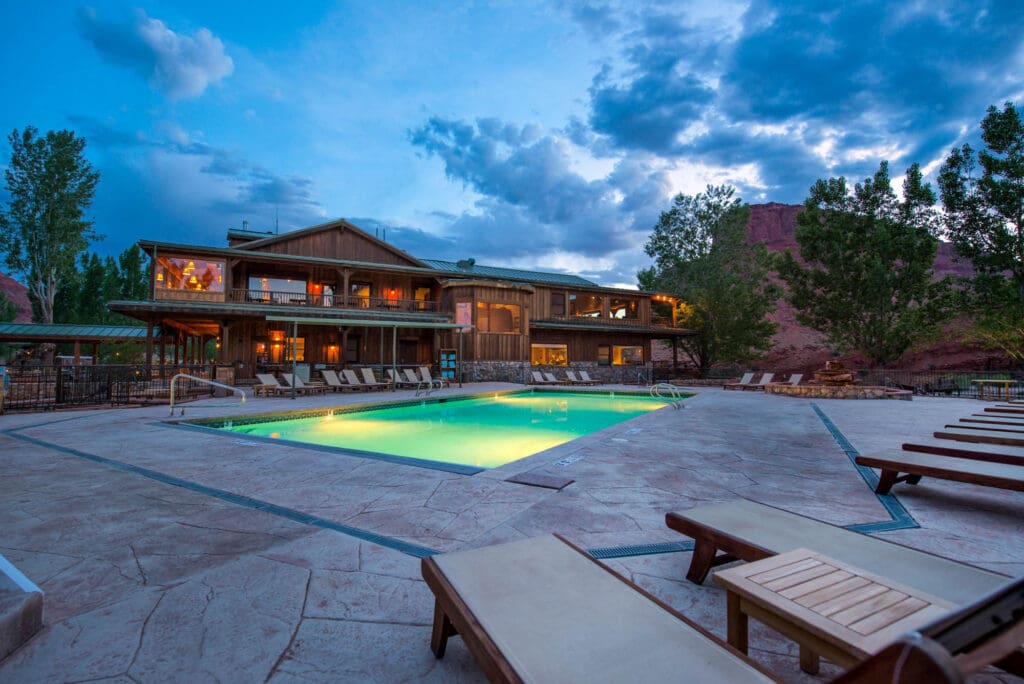 Sorrel River Ranch lodge overlooking the property pool during the evening. 