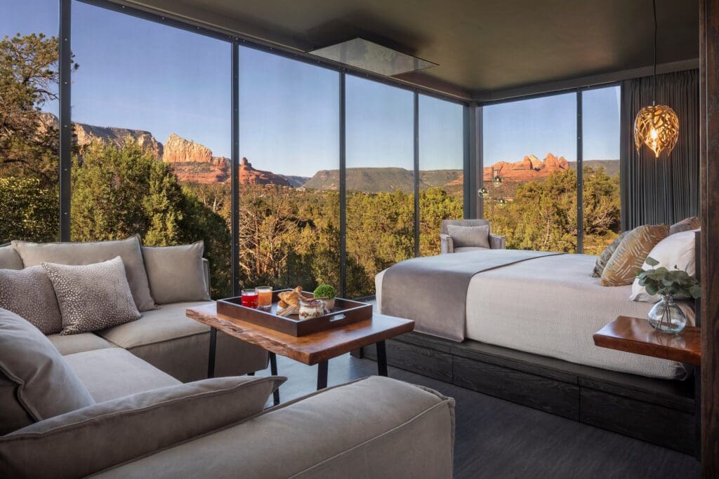 A open-window atrium with bed, couch and a charcuterie tray on a table overlooking Sedona.