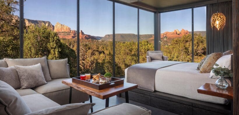 A open-window atrium with bed, couch and a charcuterie tray on a table overlooking Sedona.