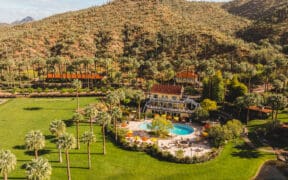 An aerial view of Castle Hot Springs Resort with main lodging and pool set near the mountains.