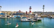 Oceanside Harbor with sailboats, lighthouse and paddle boarders in the bay.