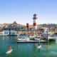 Oceanside Harbor with sailboats, lighthouse and paddle boarders in the bay.