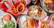 A spread of onion rings, burgers and sandwiches on a table at The Cherry Cricket.