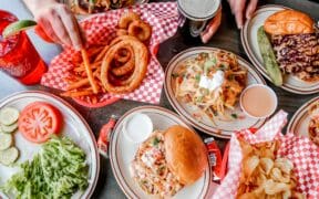 A spread of onion rings, burgers and sandwiches on a table at The Cherry Cricket.