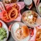 A spread of onion rings, burgers and sandwiches on a table at The Cherry Cricket.