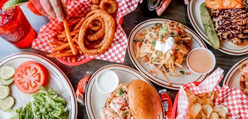 A spread of onion rings, burgers and sandwiches on a table at The Cherry Cricket.