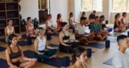 A full class of people in lotus position in a Mindbody and CorePlus pilates class.