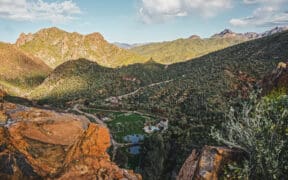 An aerial view of Castle Hot Springs resort in a valley surrounded by desert mountains.