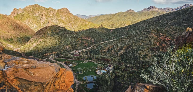 An aerial view of Castle Hot Springs resort in a valley surrounded by desert mountains.