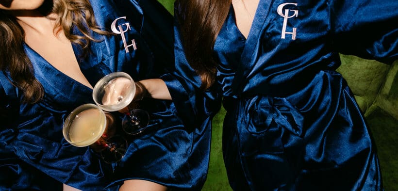 Two women in silky blue robes with GH emblems cheers with coffee drinks at Gunter Hotel in San Antonio.