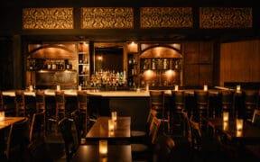 A prohibition decored bar with dark lighting and oak wood accents and seating at Nica on 4th in Downtown Austin.