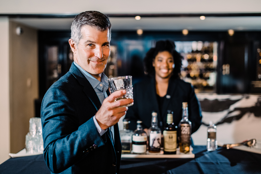 A man holds a glass of bourbon at The Oxford Hotel's Cruise Room.