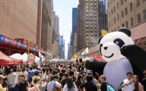 A large gathering of people in a Downtown city, celebrating Panda Fest.