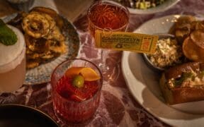 Cocktails and French-American inspired dishes are decoratively placed on a table at Society Swan in Scottsdale.