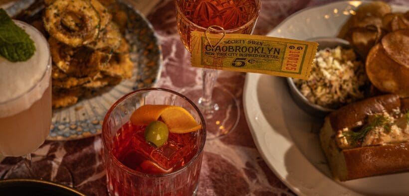 Cocktails and French-American inspired dishes are decoratively placed on a table at Society Swan in Scottsdale.