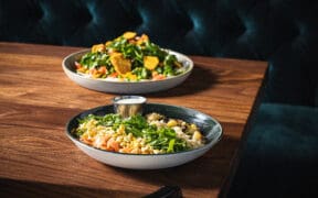 Weekend at Bernie's Salad and The G.O.A.T. Salad on a wood table booth at Sparrow restaurant in Peoria.