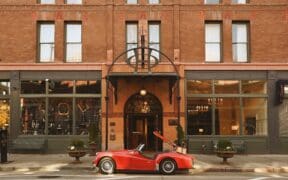 A red vintage sports care is parked at the entrance of The Oxford Hotel in LoDo Denver.