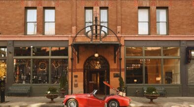 A red vintage sports care is parked at the entrance of The Oxford Hotel in LoDo Denver.