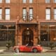 A red vintage sports care is parked at the entrance of The Oxford Hotel in LoDo Denver.