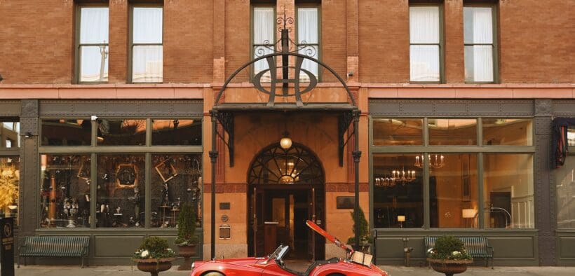 A red vintage sports care is parked at the entrance of The Oxford Hotel in LoDo Denver.